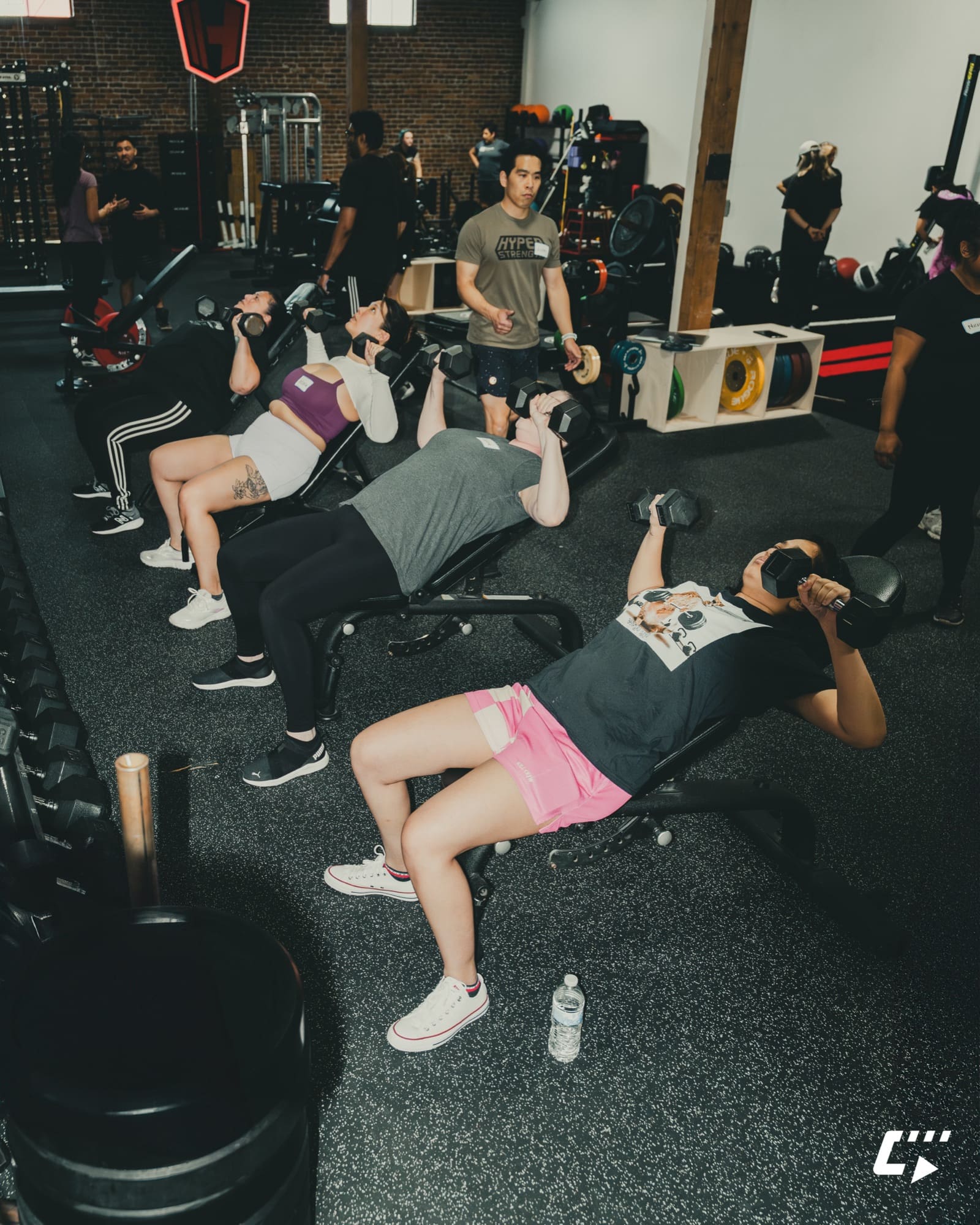 Coach supervising a small group dumbbell training session at HSC Gym
